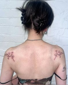 the back of a woman's neck with tattoos on her upper and lower arm