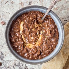 a bowl filled with chocolate and nuts on top of a counter next to a wooden spoon