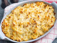 a casserole dish with cheese and meat in it on a red and white towel