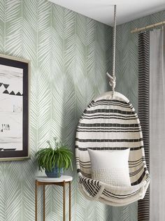 a hanging chair in the corner of a room with a potted plant next to it