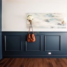 a purse hanging on the wall next to a coat rack with two flowers in it