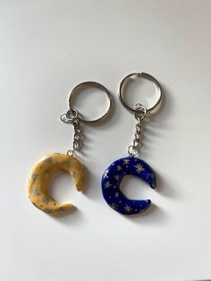 two key chains with the letters c and c painted on them, sitting next to each other