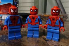 three lego spider - man figures sitting on top of a table