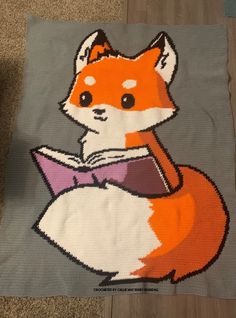 a knitted blanket with an image of a fox reading a book