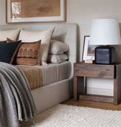 a bed sitting next to a night stand on top of a wooden table in a bedroom