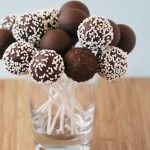 chocolate covered candies in a glass vase on a wooden table with white sprinkles