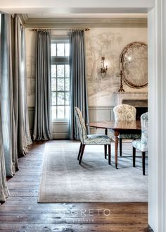 an elegant dining room with blue chairs and curtains