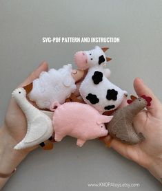 a person holding several small stuffed animals in their hands, one is white and the other is pink