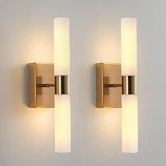 two lights are on the wall next to each other, one is gold and the other is white