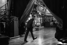 black and white photograph of man walking in front of stage