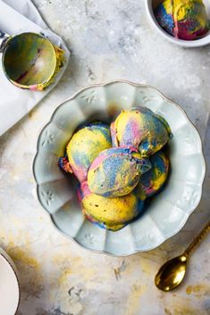 bowls filled with colorfully dyed fruit on top of a table next to utensils