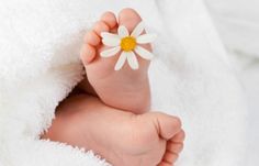 a close up of a baby's foot with a flower on it