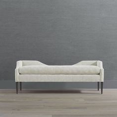 a white couch sitting on top of a hard wood floor next to a gray wall