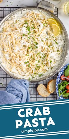 crab pasta in a skillet on a cooling rack with lemons and parsley