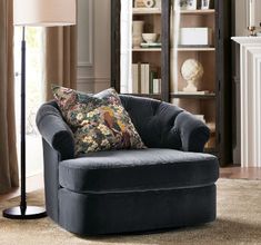 a living room scene with focus on the chair and floor lamp, bookshelf in the background