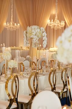 the tables are set up with white flowers and gold chairs for an elegant wedding reception