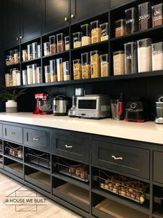 a kitchen counter with lots of food in containers on the wall and shelves above it