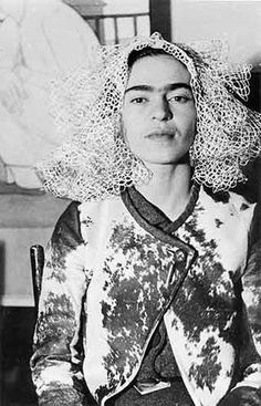 an old black and white photo of a woman with curly hair wearing a large headdress