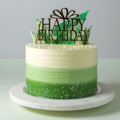 a green and white cake with a happy birthday topper on it's side