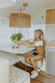 a woman sitting at a table with a potted plant