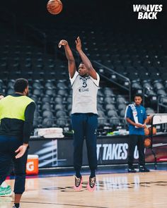 a basketball player is jumping up to dunk the ball in an indoor court with other players