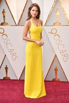 a woman in a yellow dress posing on the red carpet at an oscars event