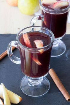 two glasses filled with liquid next to apples