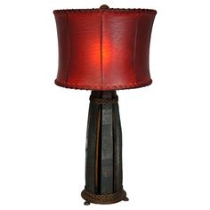 a lamp that is on top of a wooden barrel with a red shade over it