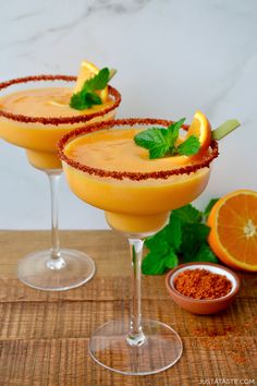 two glasses filled with orange margaritas and garnish