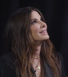 a close up of a person with long hair and wearing a black jacket, looking to the side