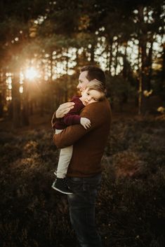 a father holding his son in the woods at sunset