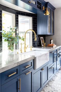 a kitchen with blue cabinets and gold faucets on the countertop, along with marble tile flooring