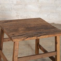 an old wooden stool sitting in front of a white brick wall with no one on it