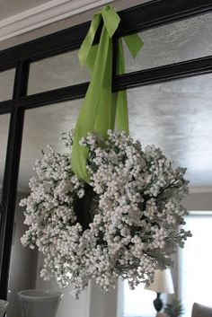 a wreath hanging from the side of a window next to a vase with flowers in it