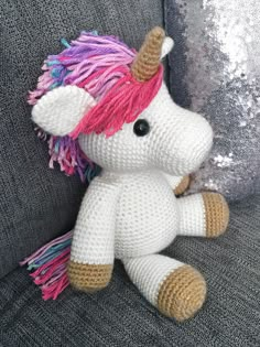 a crocheted stuffed unicorn sitting on top of a couch