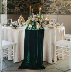 the table is set with white and green linens, silverware, candles, and flowers