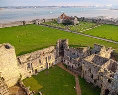 an aerial view of the ruins of a castle with water and buildings in the background