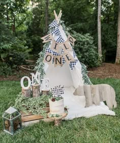 a teepee tent is decorated with greenery and other items for an outdoor birthday party