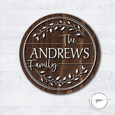 the andrews family logo on a wooden plaque with leaves and branches around it, in white lettering