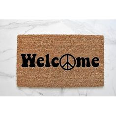 a door mat that says welcome with a peace sign in the center and black lettering on it