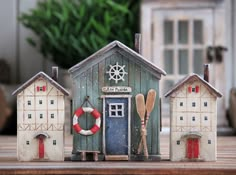 three small wooden houses sitting on top of a table