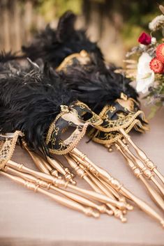 three black and gold masquerades are laying on a table with flowers in the background