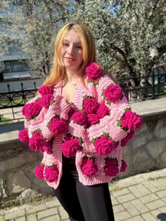 a woman is wearing a pink crocheted sweater with roses on it