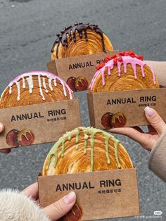 four people holding up some breads with icing on them