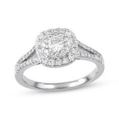 a white gold ring with diamonds on the sides and an oval shaped halo setting in the center