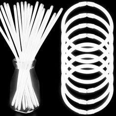 several white sticks in a glass vase with the top lit up and next to it is a black background