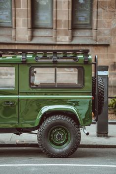 a green land rover parked on the side of the road