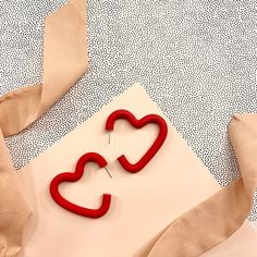 a pair of red heart shaped earrings sitting on top of a piece of paper