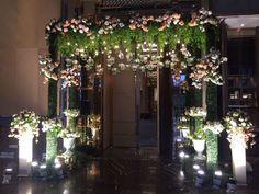 an entrance decorated with flowers and greenery for a wedding or reception in the evening