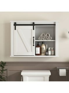 a white toilet sitting next to a wooden cabinet with sliding doors on the door and shelves above it